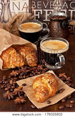 Coffee in glass mug  and croissants on  wooden rustic background
