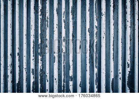 An old rusty fence consisting of pipes. In blue tones.
