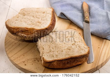 sliced northern irish breakfast bap on a round wooden board with bread knife