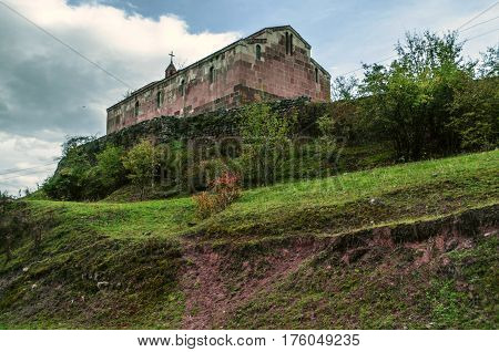 Medieval monastery on the hill surrounded by old stone wall in the autumn overcast day