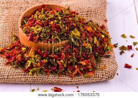 Colored spices with pepper in a cup and burlap on a wooden table