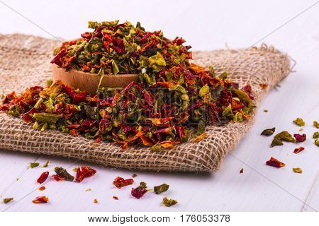 Colored spices with pepper in a cup and burlap on a wooden table