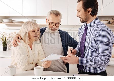 Looking for successful financial investment . Friendly delighted curious senior couple owners meeting with financial adviser and consult him while choosing the variant for investment