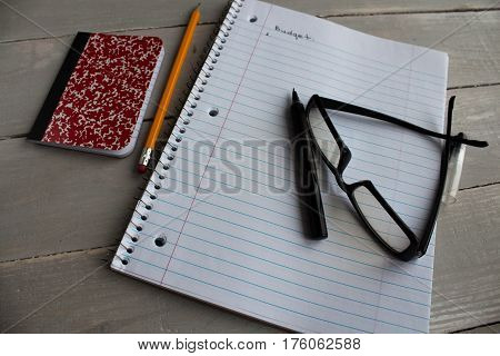 a notebook glasses pen pencil budget wooden background