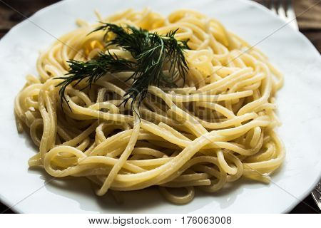 the plate with spagetti and dill wooden background