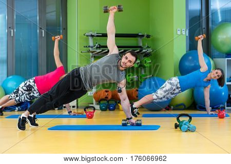 group of people working out in a gym with a dumbbell.
