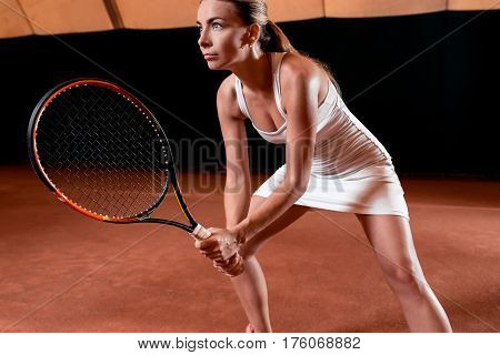 Sportswoman at the tennis court with racquet. Indoor tennis court