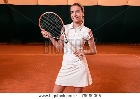 Sportswoman at the tennis court with racquet. Indoor tennis court