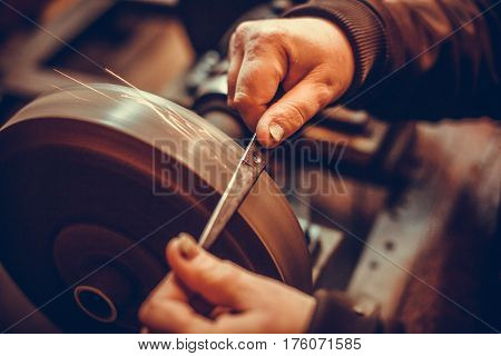 Close up shot of a man's hands sharpening a scissors.