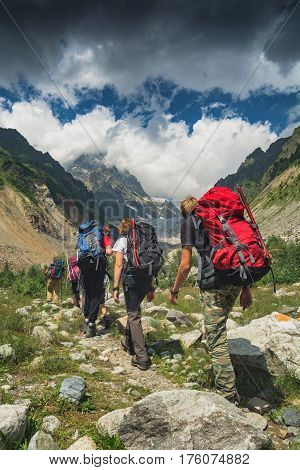Group of hikers with backpacks climb to the peak of mountain. Caucasian mountains Georgia Svaneti region.