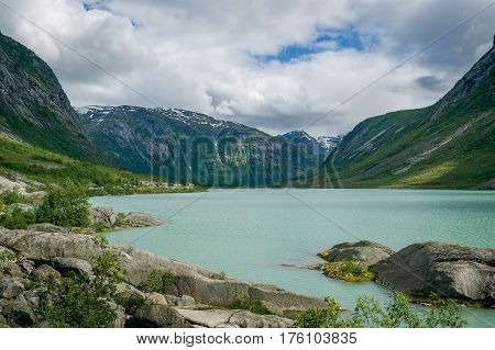 Panoramic view of Nigardsbreen glacier melted water lake and fjord shore mountains. There is a beautiful hiking path to the ice formations. Nigardsbreen, Norway.