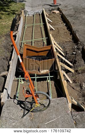 A measuring wheel lies in front of a curb and street construction project