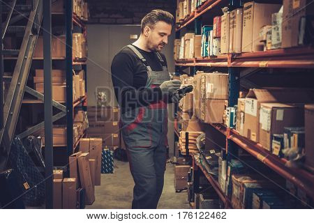 Storekeeper with mobile computer working in a warehouse.