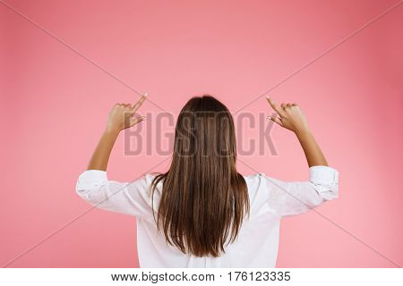 Young woman in trendy spring outfit posing with hands up on light pink background
