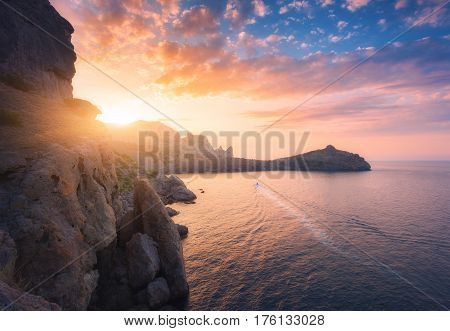 Mountain landscape at sunset. Beautiful view from the hill on the blue sea cape cliffs and colorful sunny sky with orange clouds in the evening. Travel in Europe in summer. Nature background