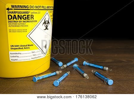 Used Needles laying next to a sharps bin