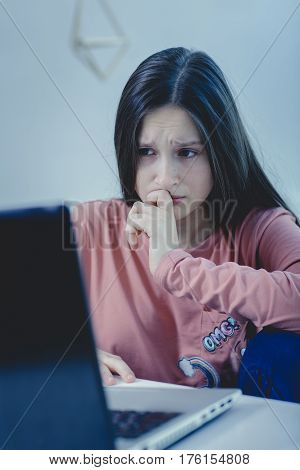 sad and scared female teenager with computer laptop suffering cyberbullying and harassment being online feeling desperate and humiliated in cyber bullying concept