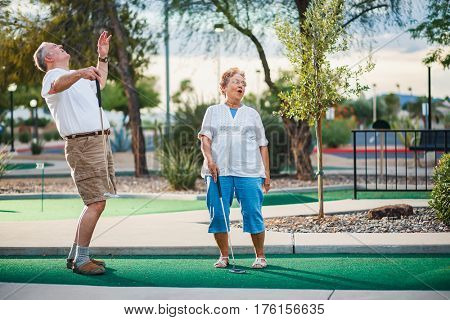 retired couple having fun playing mini golf