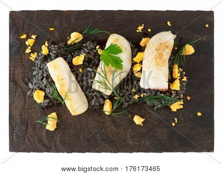 Risotto cooked with squid ink, seared calamar on wooden board, isolated on white