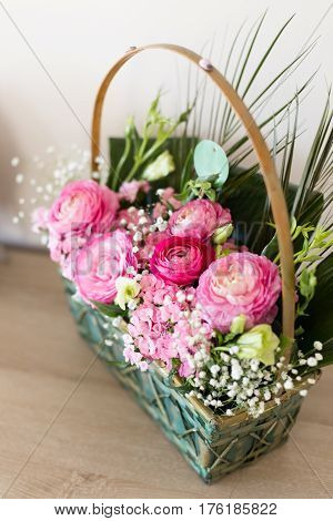 Flower arrangement in basket with dark and light pink ranunculus and austeria view from above with central flowers in focus and other flowers blurred