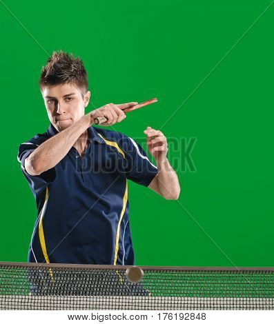 Young male athlete playing table tennis on green chromakey background