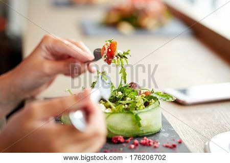 food, culinary, haute cuisine and people concept - woman eating cottage cheese salad with vegetables and dried raspberries at restaurant or cafe