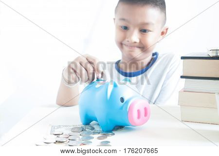 Little Asian Boy Smiling To Saving Money In Piggy Bank White Background With Copy Space