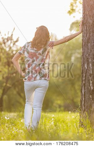 Girl toucing the tree and enjoying in the forest.