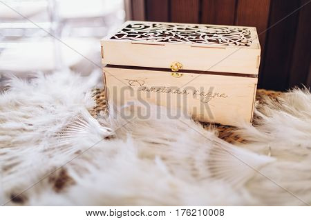 Vintage wooden box which is a family treasury on wedding, standing among white feathers