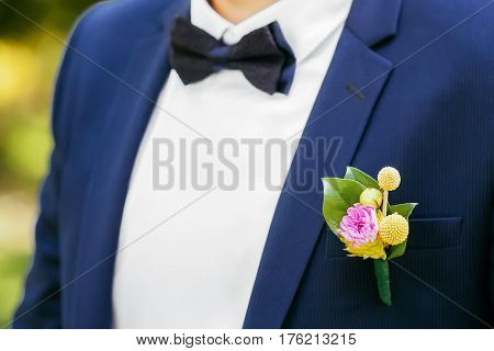 Pink peon boutonniere pinned to a grooms blue jacket
