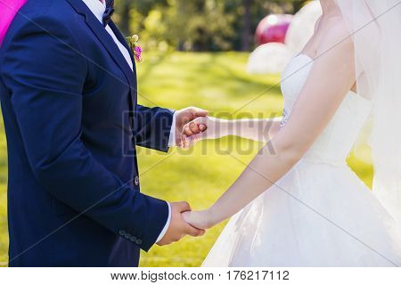 Newlyweds staying arm in arm, with wedding rings, closeup