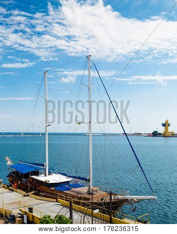 Two-masted wooden sailboat moored in harbor. The sails are lowered