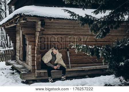 Brave Viking Warrior Sharpening Axe Before Battle In The North, Scandinavian Man With Mohawk Sitting