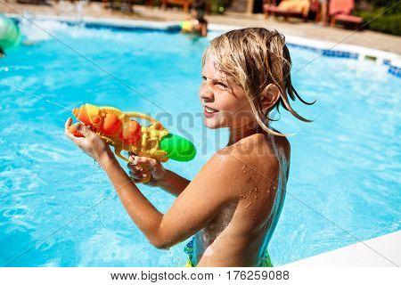 Cheerful children playing waterguns, rejoicing, jumping, swimming in pool. Copy space
