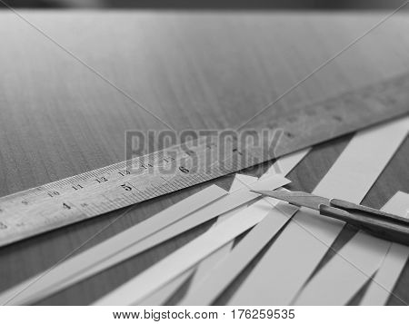 Cutter knife with stainless ruler and strip of white paper in black and white