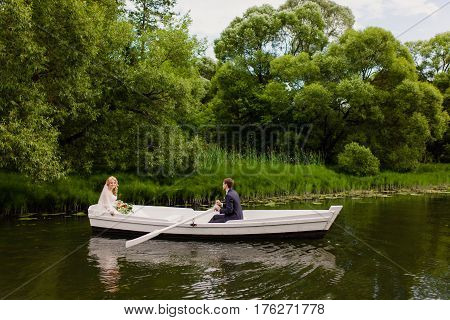 The groom and bride are floating on the river on the white boat