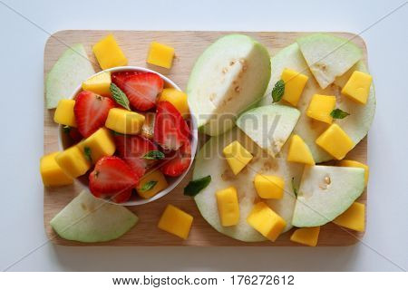 Fresh fruits - guava mango and strawberry with leaves of mint on the white background.