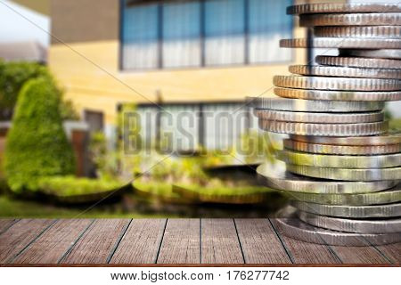 Business finance and real estate concepts Empty wood table top Money coin stack with blurred home garden background.