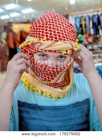 Young woman of European appearance wearing Arabic headdress. The girl looks at the camera close-up. Portrait