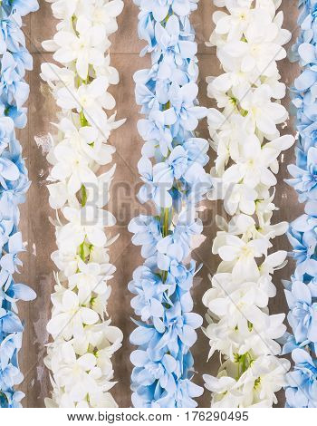 White and blue artifical flower bunch is hanging near the wall for decortion in the hall.