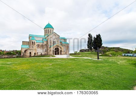 old restored temple of David the Builder Kutaisi 2014. before the temple there is a stone fence and high conifer
