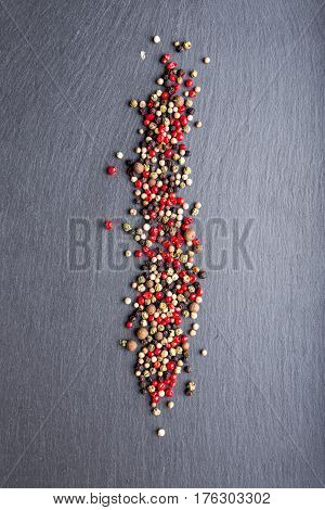 colored peppers scattered on the slate top view