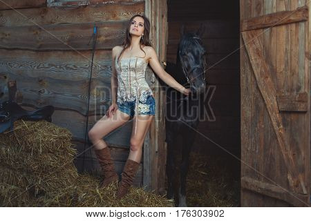 Woman holds a horse for a bridle she has a pensive face.