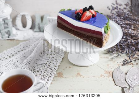 Modern trendy mousse cake with blue marble mirror glaze. strawberry and blackberries decor. Selective focus. Space for text wooden background.