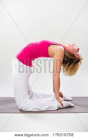 Woman exercising yoga indoor-variation of Camel pose/Ustrasana