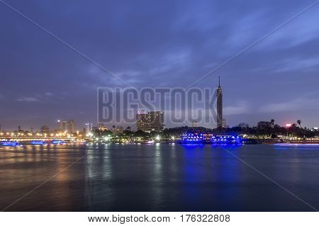 Cairo city center at twilight the Kasr El Nile Bridge and the island of Zamalek with its colorful boats on the Nile river.