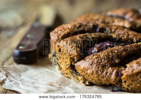 Vegan eggless whole wheat plum cake on parchment paper knife wood kitchen table close up rustic kinfolk style