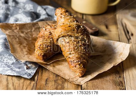 Whole wheat croiisants with sesame seeds on wood kitchen table towel enamel mug cozy morning atmosphere kinfolk rustic style