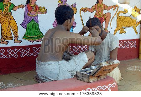 HYDERABAD,INDIA-MARCH 3 :Rural Indianr man a barber figurine do haircut in traditional way as seen in villages in Shilparamam on March 3,2017 in Hyderabad,India.