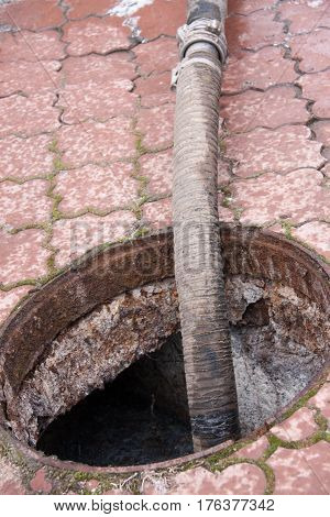 man pumping sewage from the drain hole.